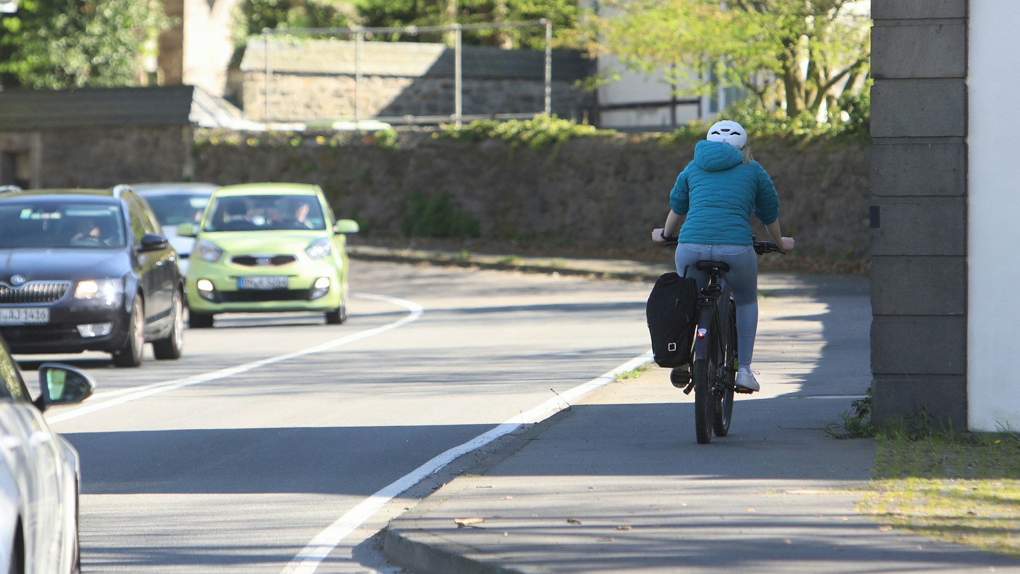 Eine Radfahrerin fährt auf dem relativ schmalen Fuß-Radweg entlang der stark befahrenen Landesstraße 268 in Höhe des Klosters Heisterbach.
