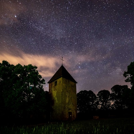 Der Wollseifener Kirchturm und einige Baumkronen ragen in den Sternenhimmel.