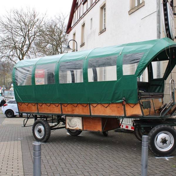 Ein Planwagen steht verkeilt an einer Hauswand.