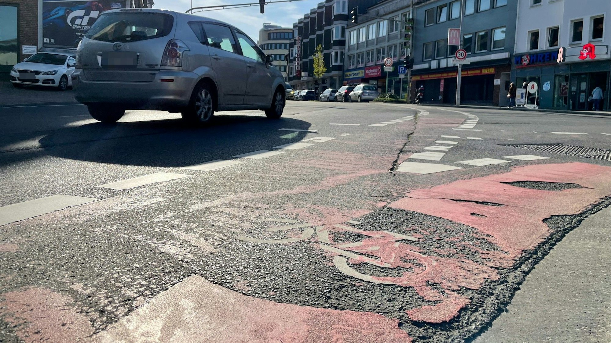 Das Foto zeigt einen Radweg in Bergheim, dessen Farbe abgesplittert ist.