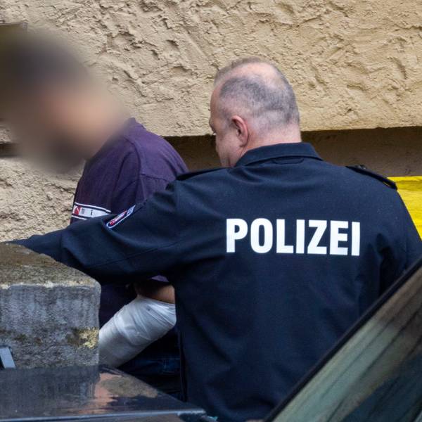 Ein Tatverdächtiger wird von einem Polizeibeamten in das Gerichtsgebäude geführt.