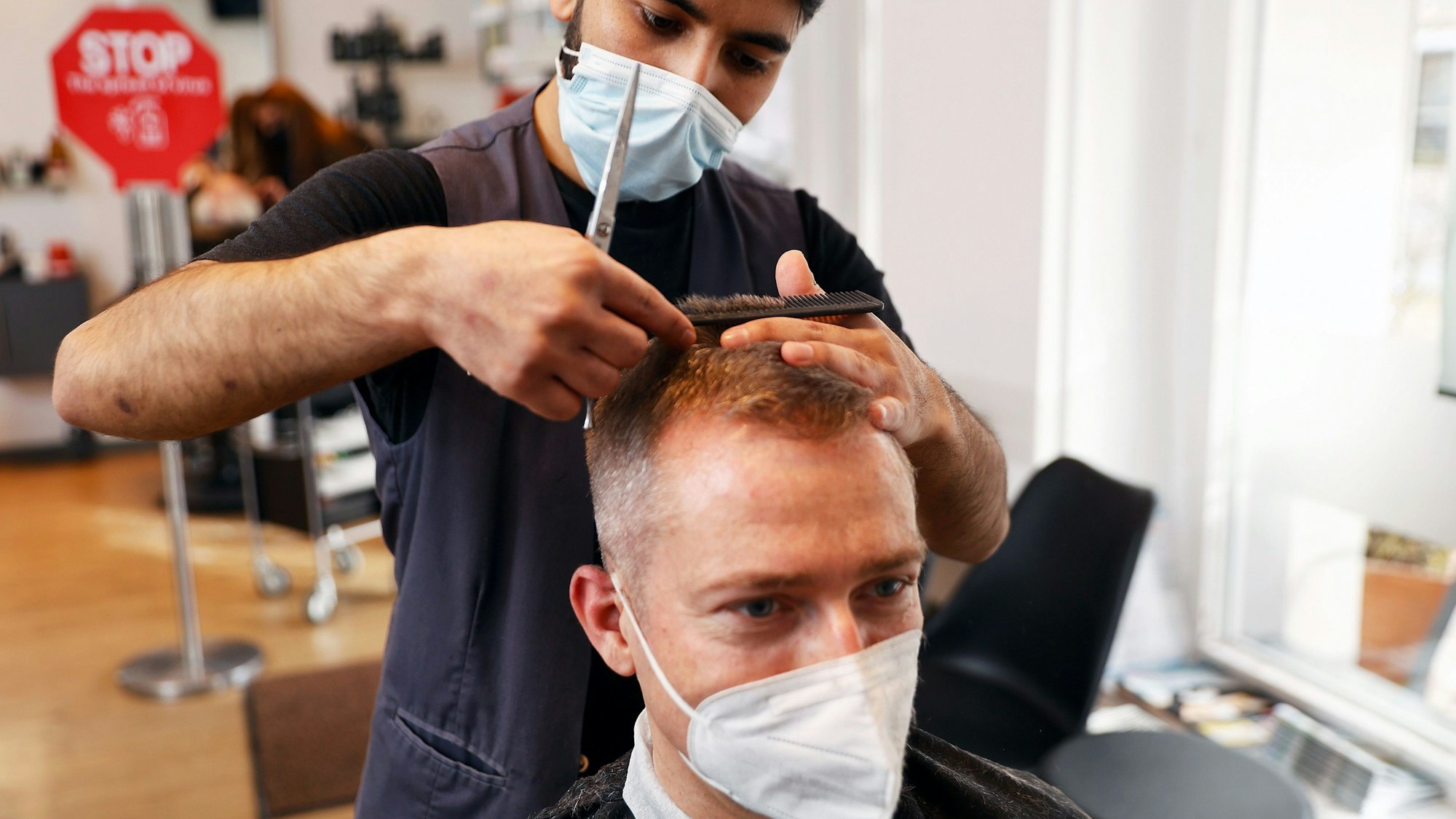 Der Friseur Noor Agha Karimi frisiert einen Kunden im Friseursalon Mac Hair in Wannsee.