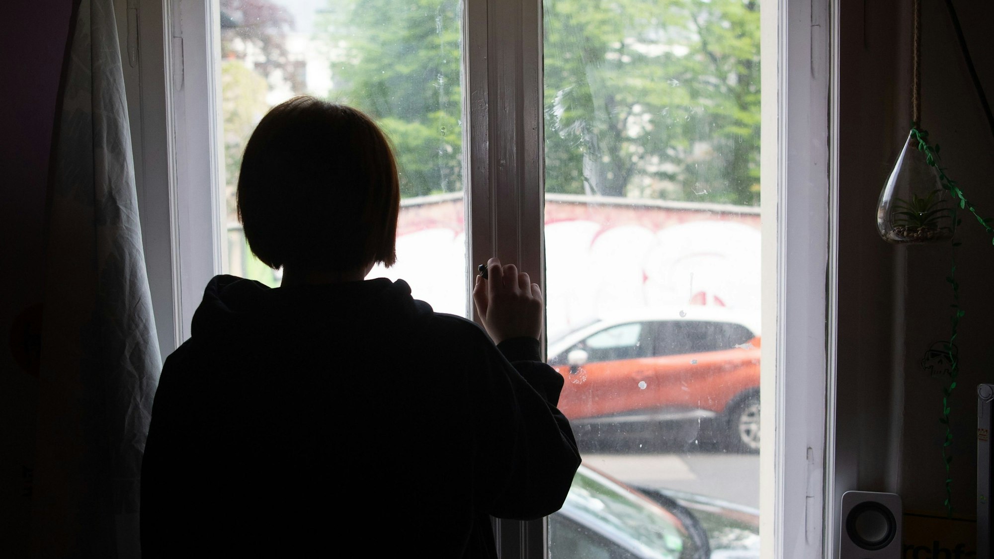 Illustration. Eine Jugendliche blickt aus einem Fenster.