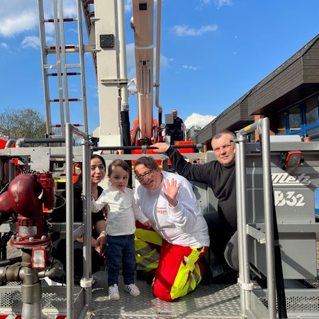 Das Foto zeigt den kleinen Damian auf einer Drehleiter. Mit seinen Eltern hat er Feuerwache Kerpen besucht und sich bei seinen Rettern bedankt.