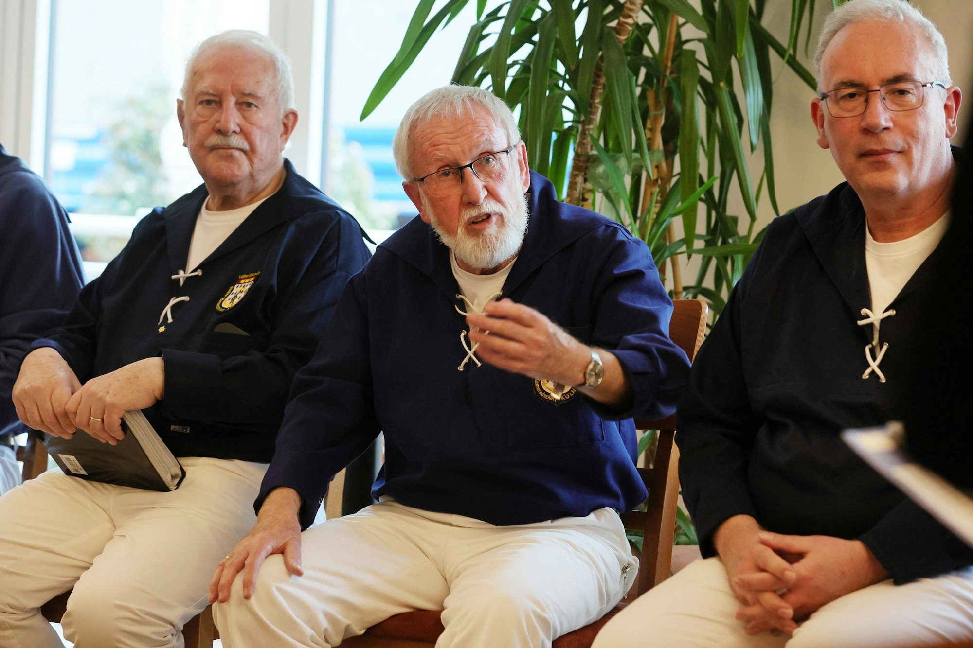 Drei Sänger in blauen Hemden mit weißer Kordel und weißen Hosen