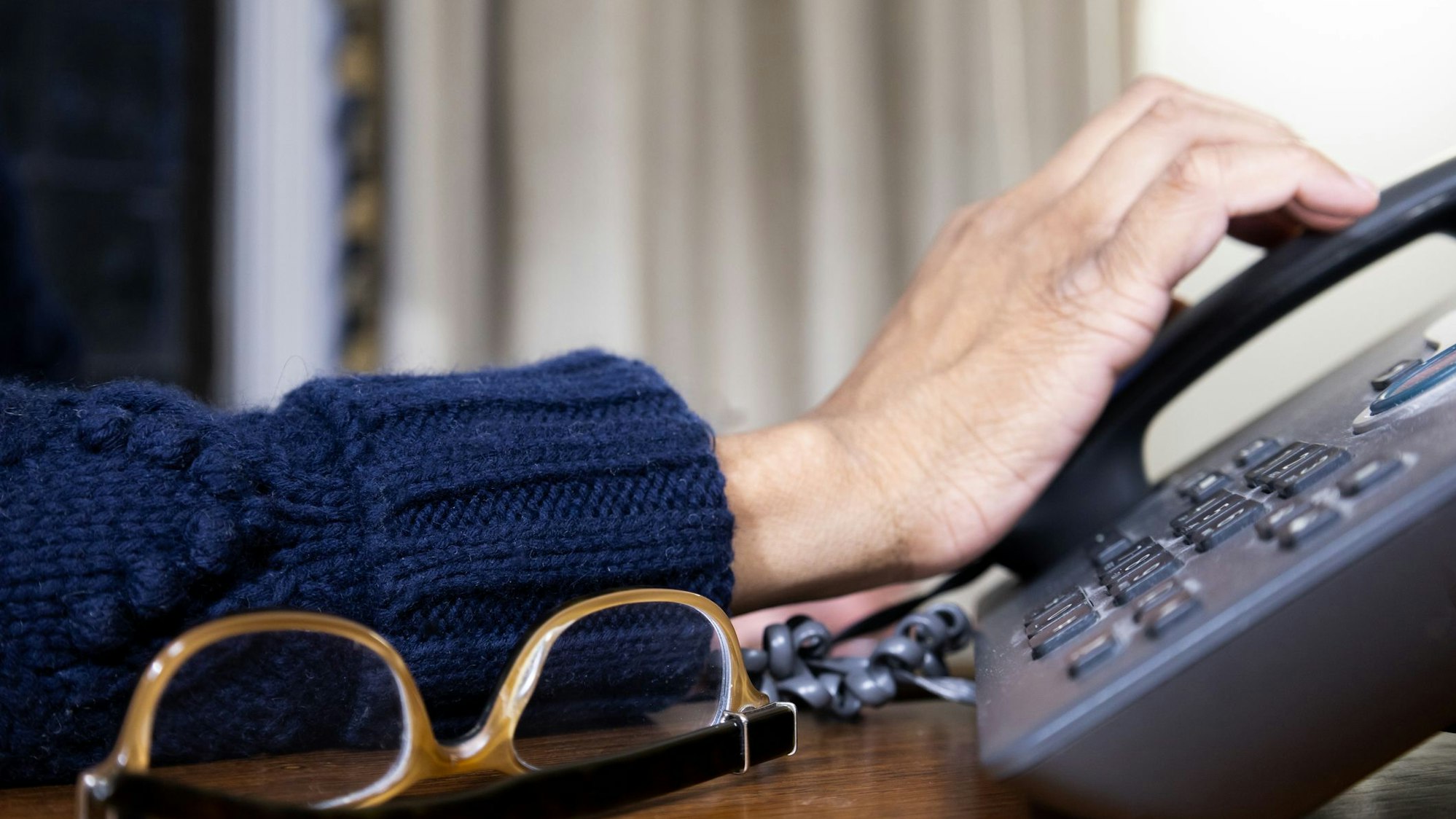 Eine Hand greift nach einem Telefonhörer.