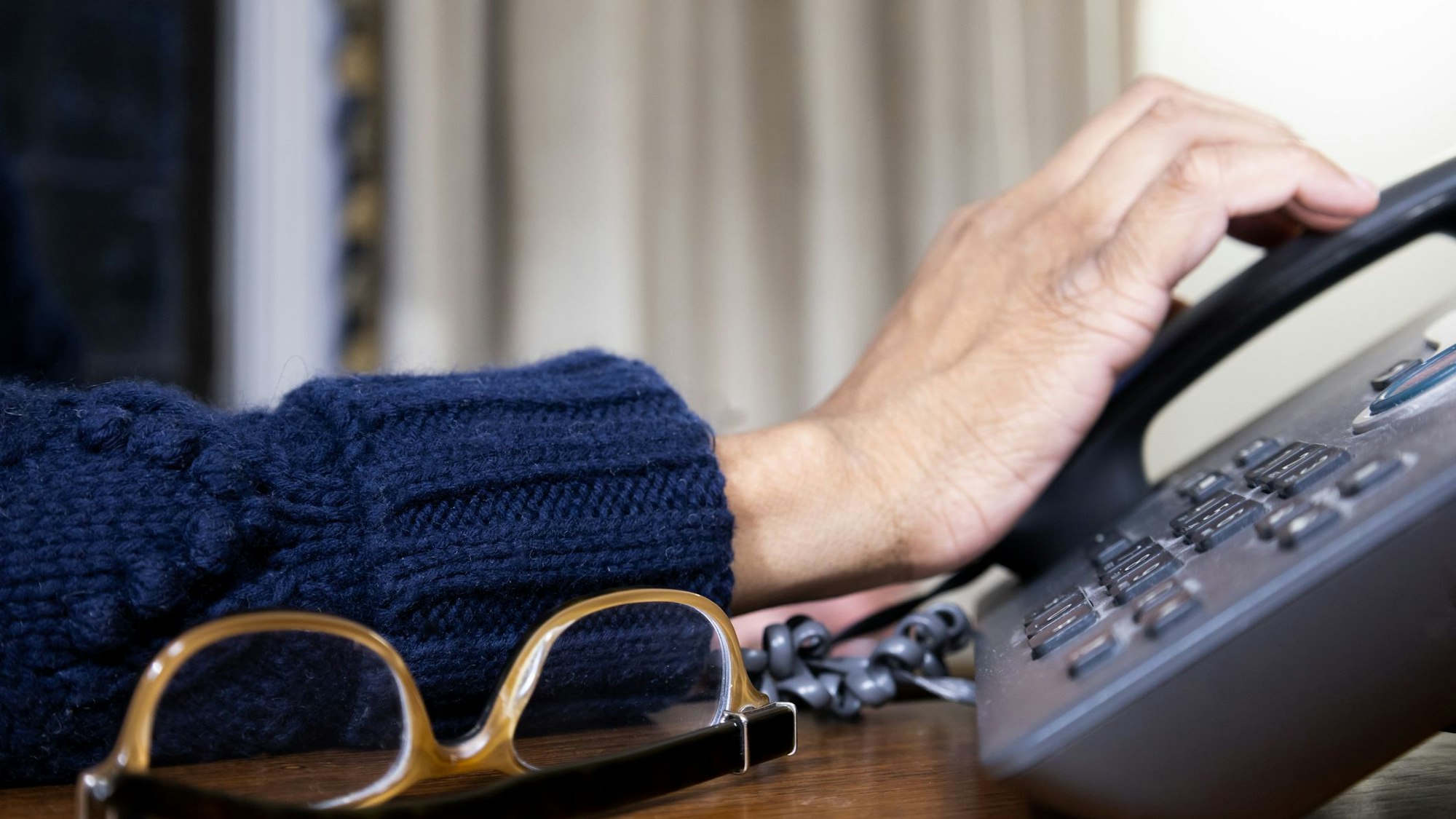 Eine Hand greift nach einem Telefonhörer.