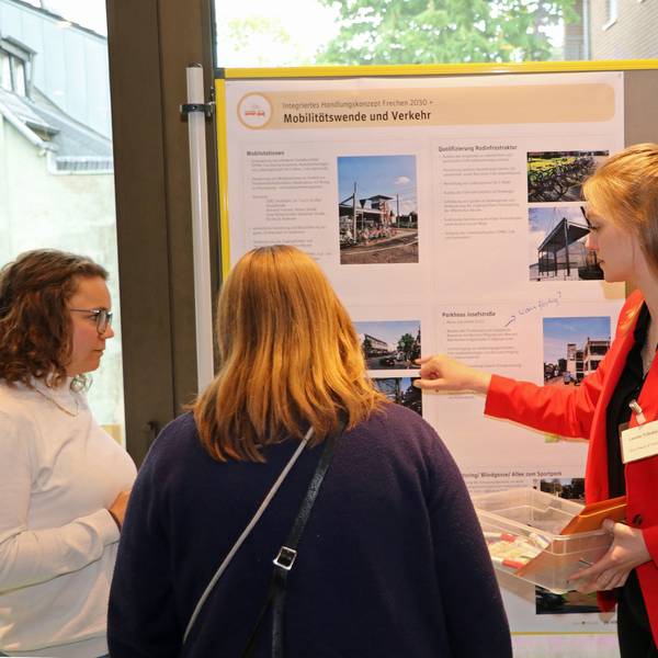 Das Foto zeigt Teilnehmer der Veranstaltung. Sie diskutieren an Schautafeln über verschiedene Projekte zur Verschönerung der Frechener Innenstadt.