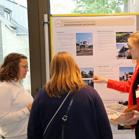 Das Foto zeigt Teilnehmer der Veranstaltung. Sie diskutieren an Schautafeln über verschiedene Projekte zur Verschönerung der Frechener Innenstadt.