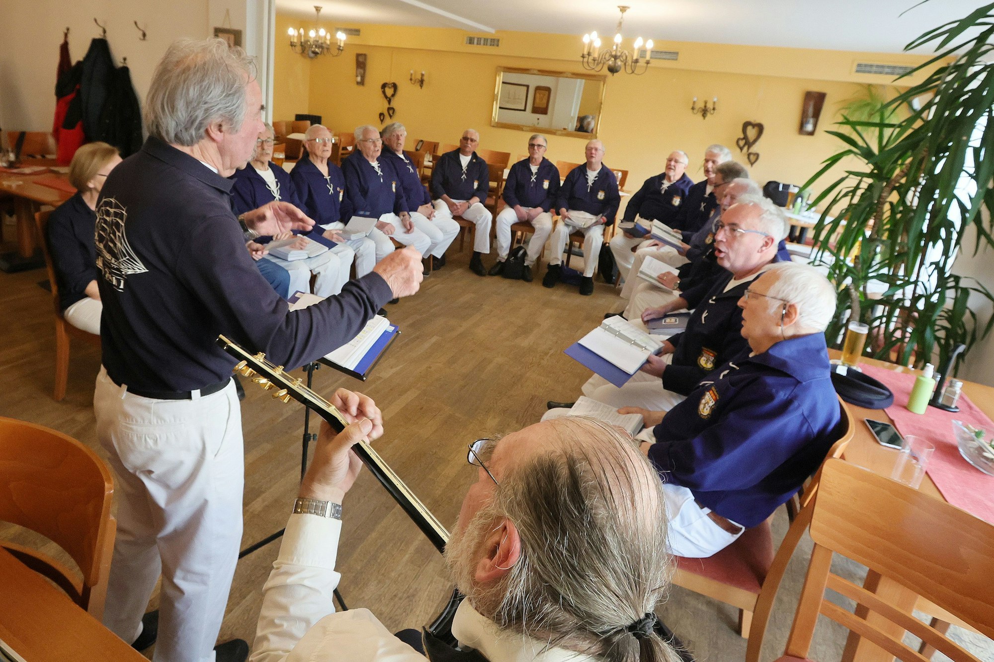Die Sänger sitzen bei der Probe im einem Lokal.