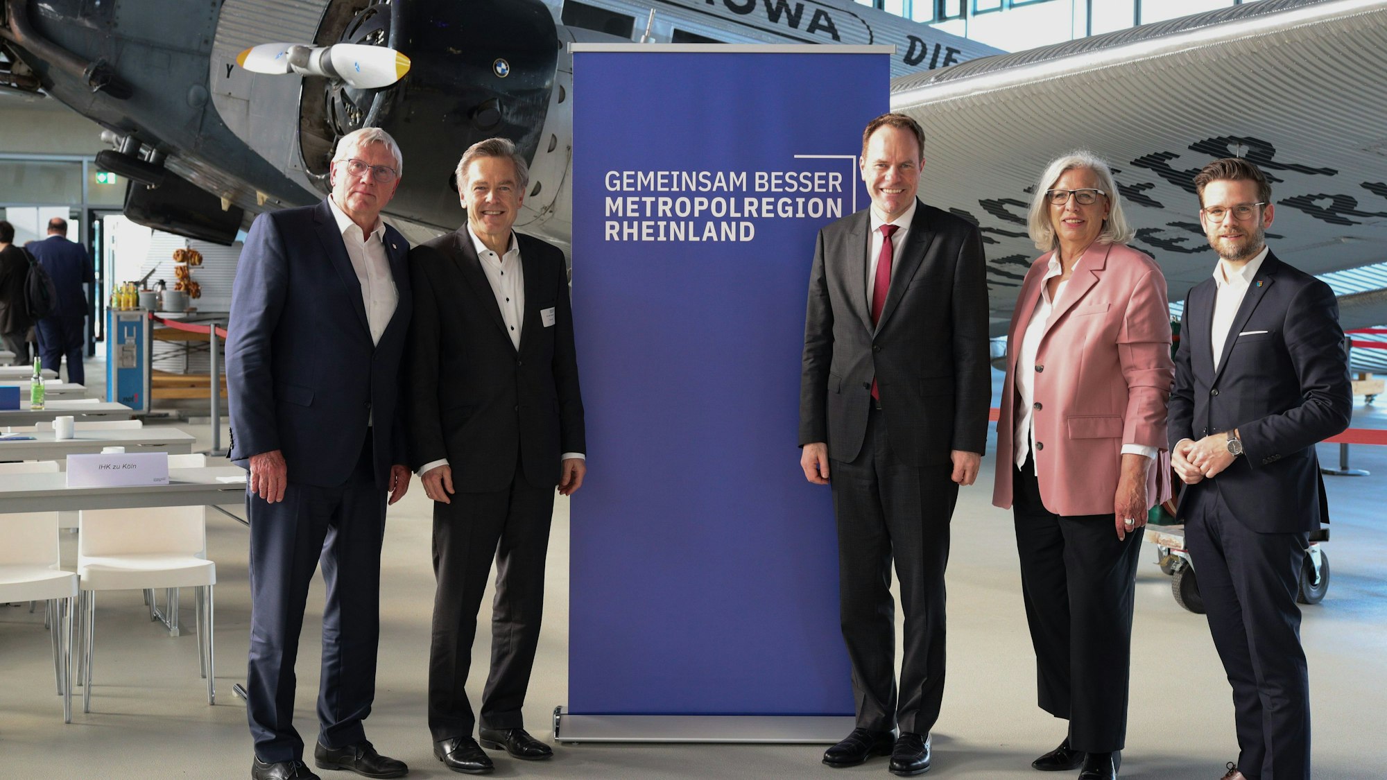 Der Vorstand der Metropolregion Rheinland steht vor einem Aufsteller des Verbands.