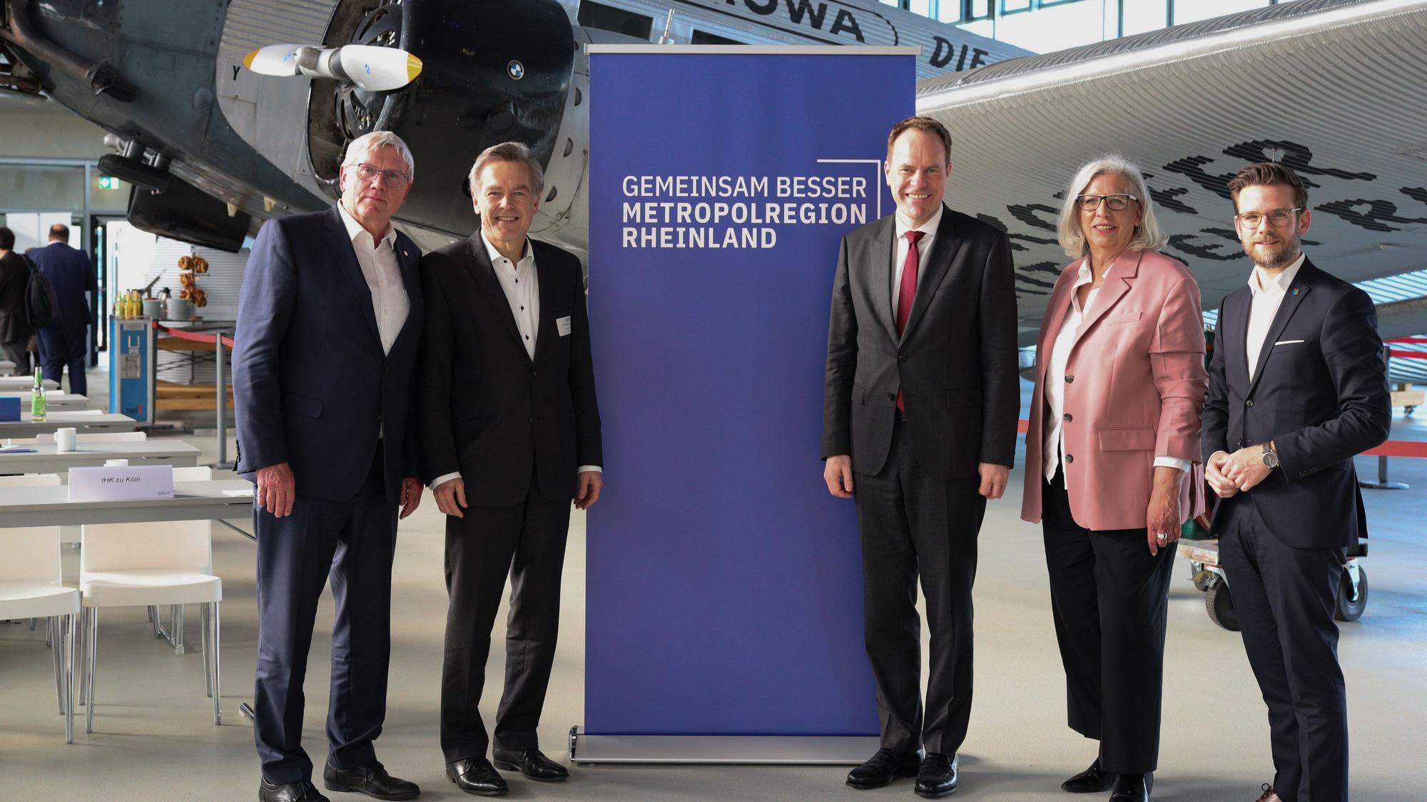 Der Vorstand der Metropolregion Rheinland steht vor einem Aufsteller des Verbands.