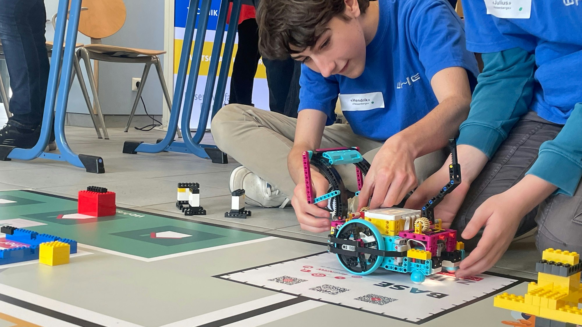 Schüler nimmt letzte Anpassungen am Roboter vor der entscheidenden Runde vor.