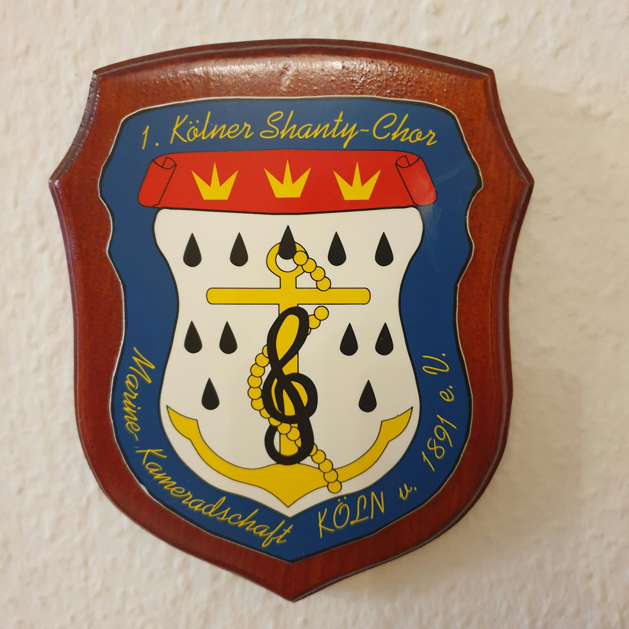 Das Emblem des Chors zeigt einen Anker mit einem Notenschlüssel.