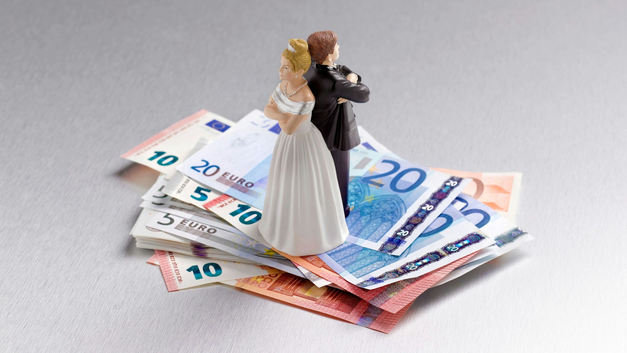 Brautpaar als Figur steht mit dem Rücken zueinander auf einigen Euroscheinen