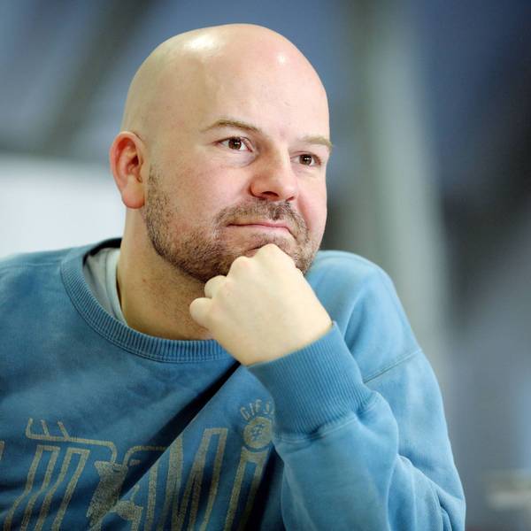 Manuel Moser stützt sich das Kinn mit der Hand. Er hat eine Glatze und einen 3-Tage-Bart. Er trägt einen blauen Pulli.