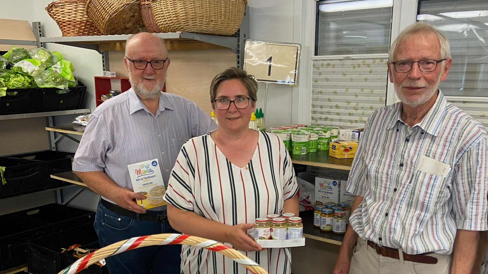 Die drei stehen im Raum der Tafel und lächeln in die Kamera. Kerstin Höfer hat eine Palette mit Babynahrung in der Hand. (Archivbild)