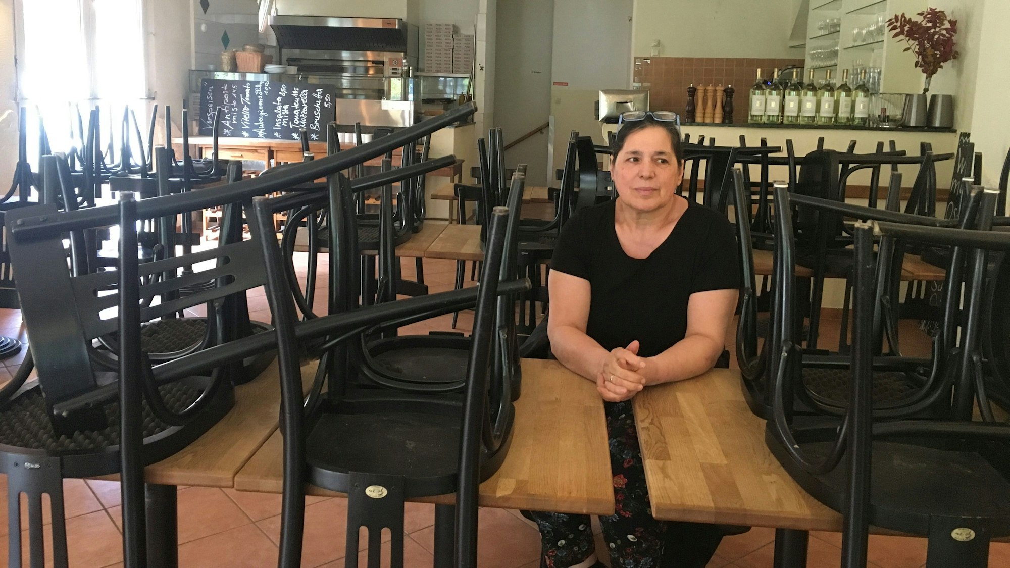 Frau im Lokal zwischen hochgestellten Stühlen