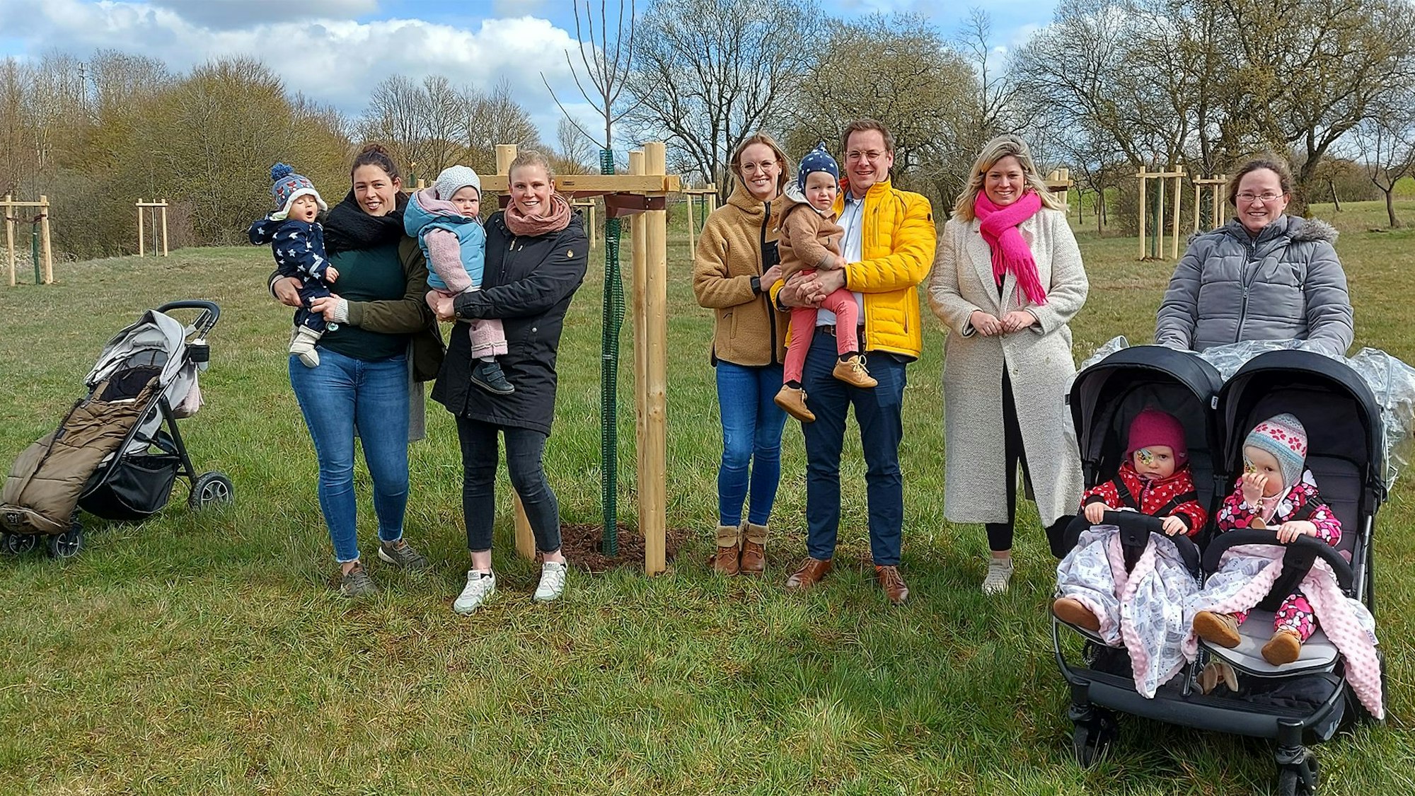 Mehere Familien stehen mit Bürgermeisterin Jennifer Meuren (2.v.r.) auf der Neubürgerbaumwiese.