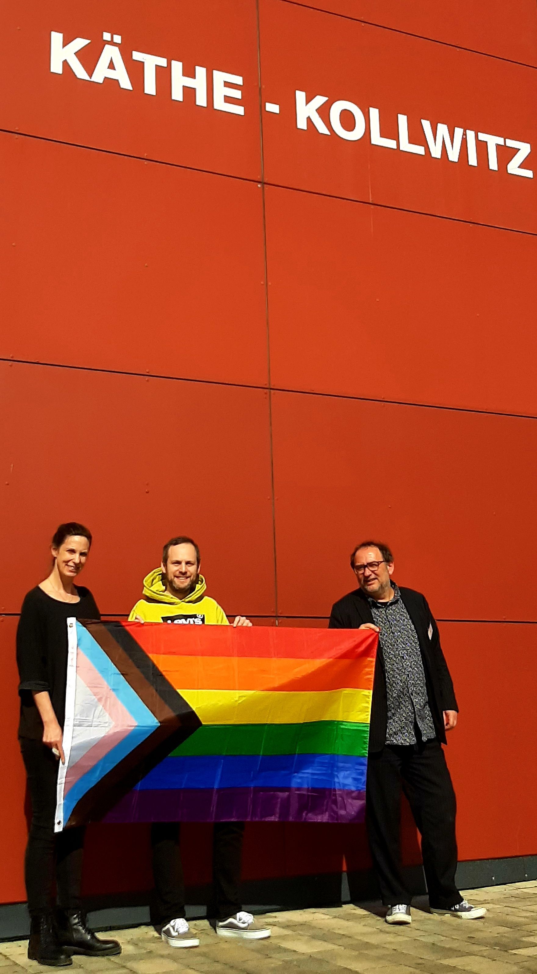 Nanni Przibylla, Frederik Podschun und Lamby Georgopoulos 8v.l.) mit der LGBTQ- und Trans-Pride-Flagge.