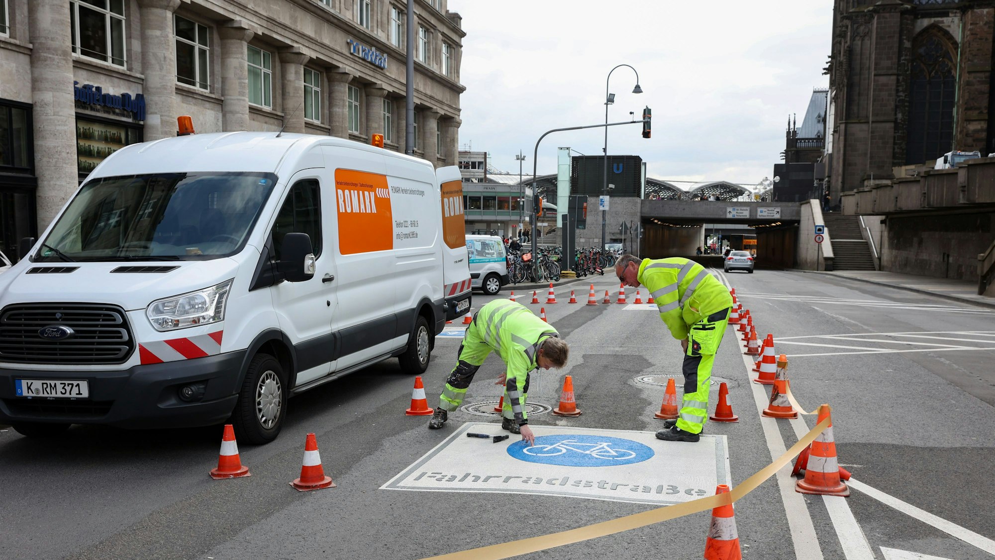 Zwei Arbeiter bringen die Piktogramme für die Fahrradstraße auf.