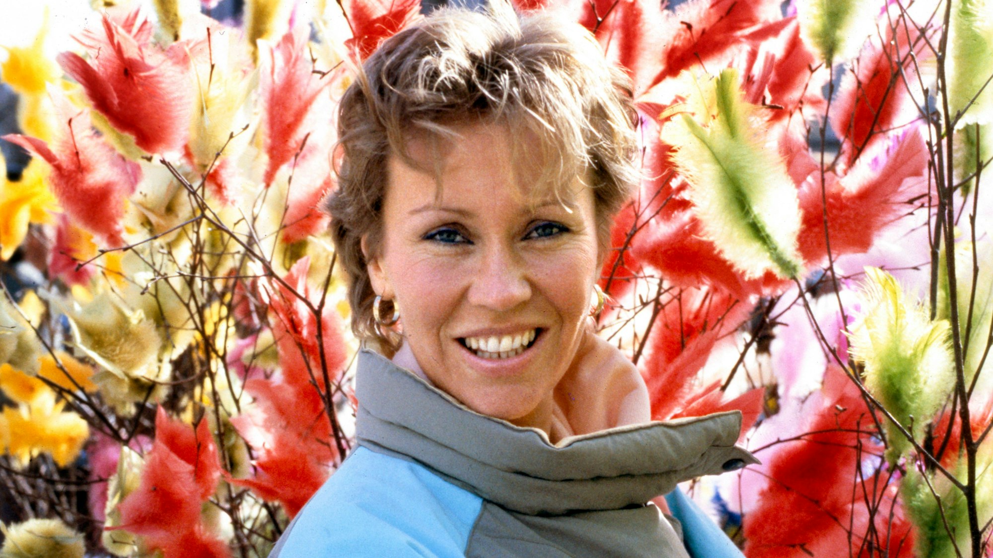 Agnetha Fältskog im Jahre 1985. Sie steht vor bunten Federn.