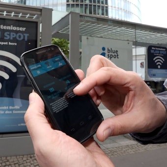 Handynutzer wählt sich an einer Haltestelle in Berlin ins Wlan-Netz ein.