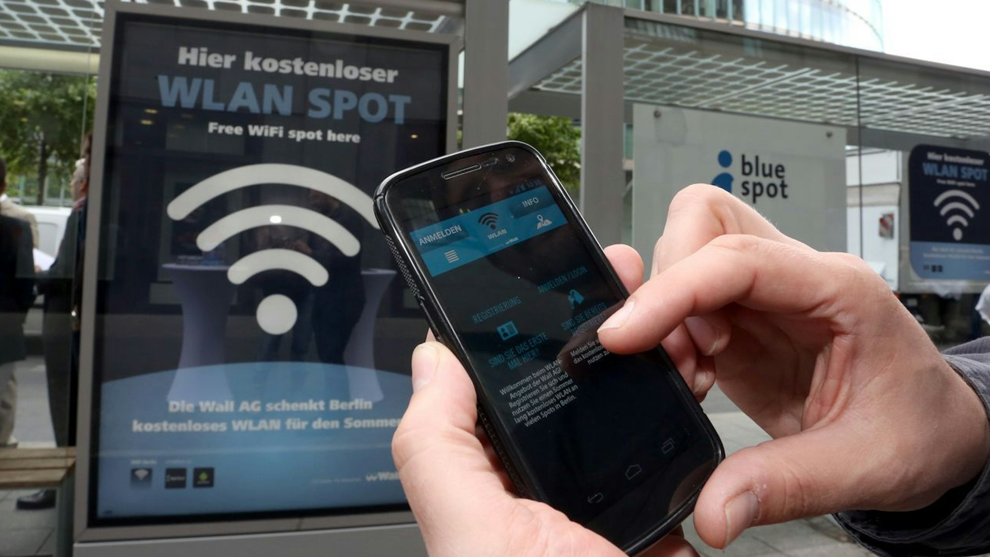 Handynutzer wählt sich an einer Haltestelle in Berlin ins Wlan-Netz ein.