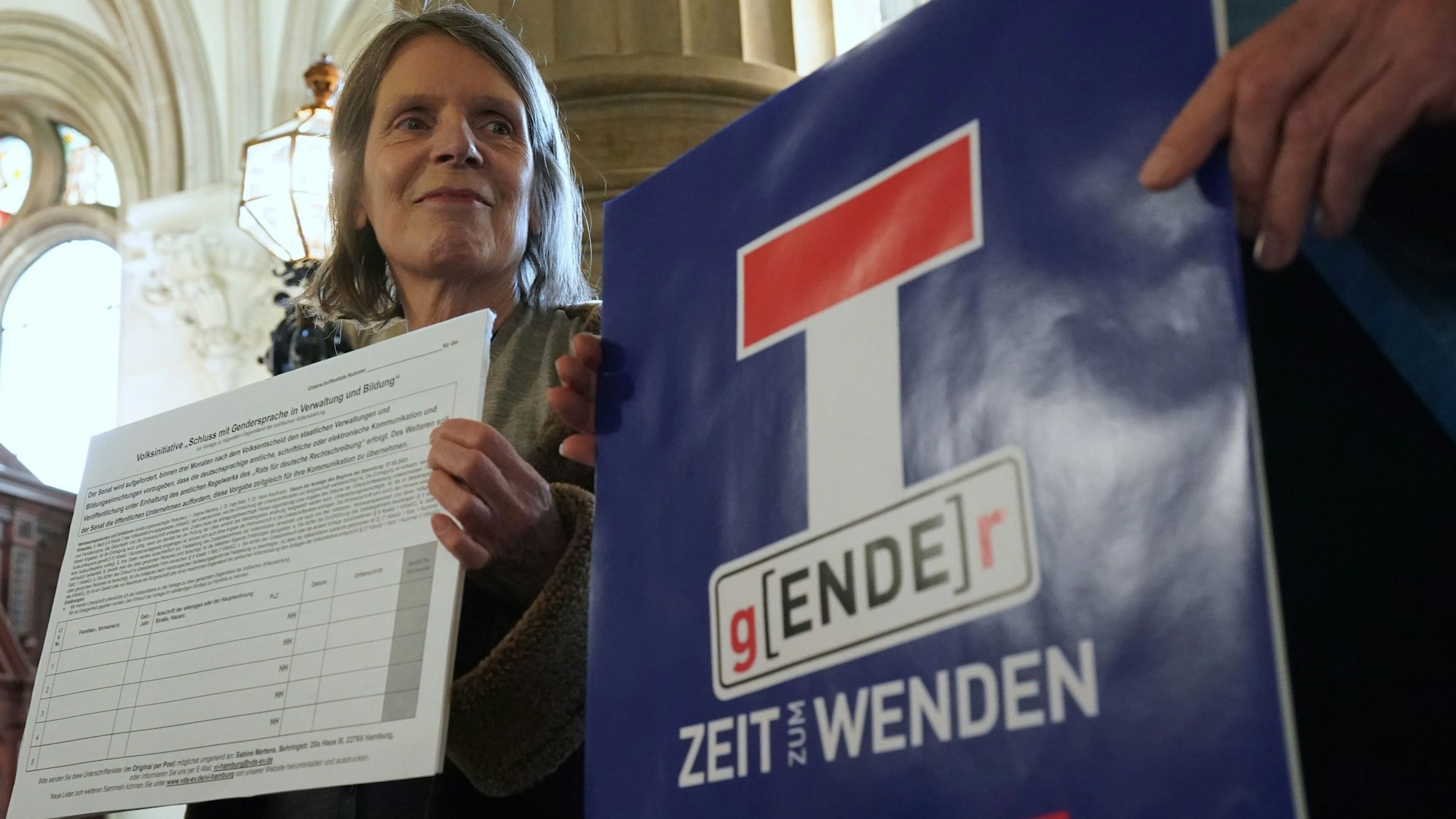 Sabine Mertens, Gründerin der Initiative „Schluss mit Gendersprache in Verwaltung und Bildung“, blickt auf ein Plakat mit der Aufschrift „Gender-Ende – Zeit zum Wenden“ im Hamburger Rathaus. In der Hand hält sie eine Unterschriftenliste.
