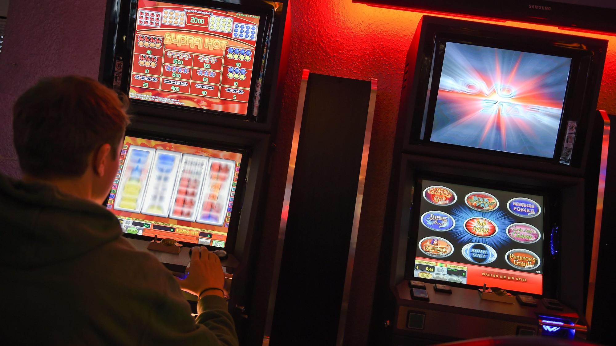 Ein junger Mann spielt an einem Spielautomaten.