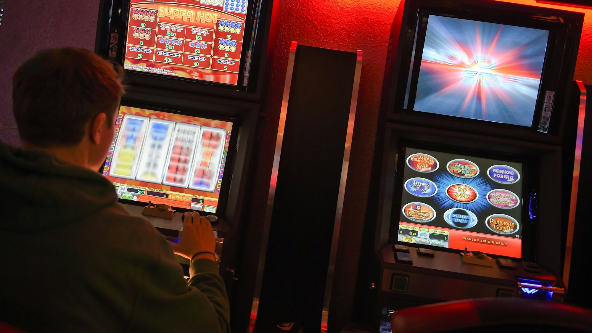 Ein junger Mann spielt an einem Spielautomaten.