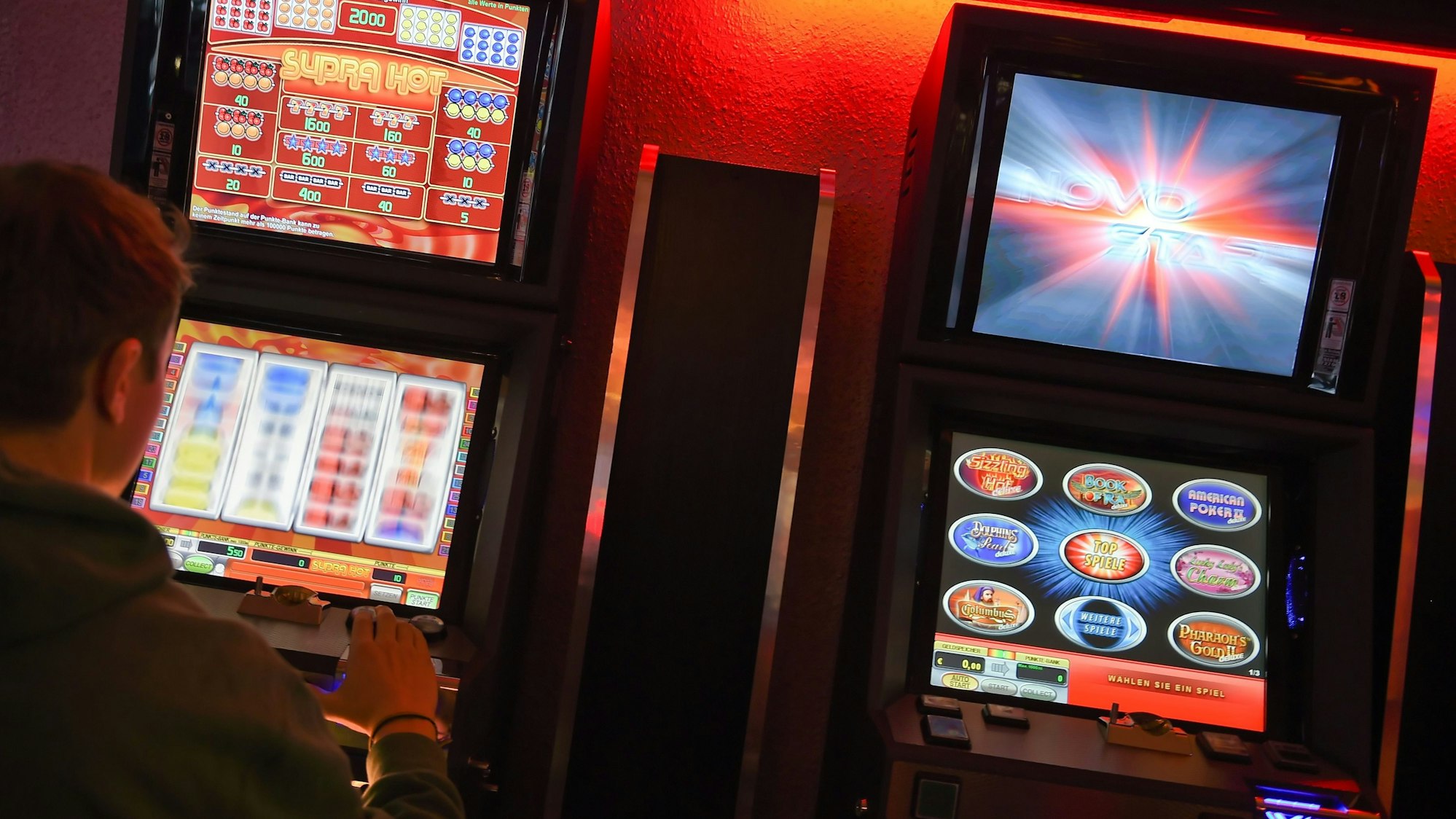 Ein junger Mann spielt an einem Spielautomaten.