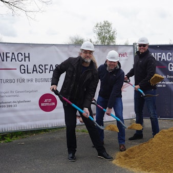 Die Vertreter von Plusnet schaufeln vor Info-Bannern symbolisch Sand.