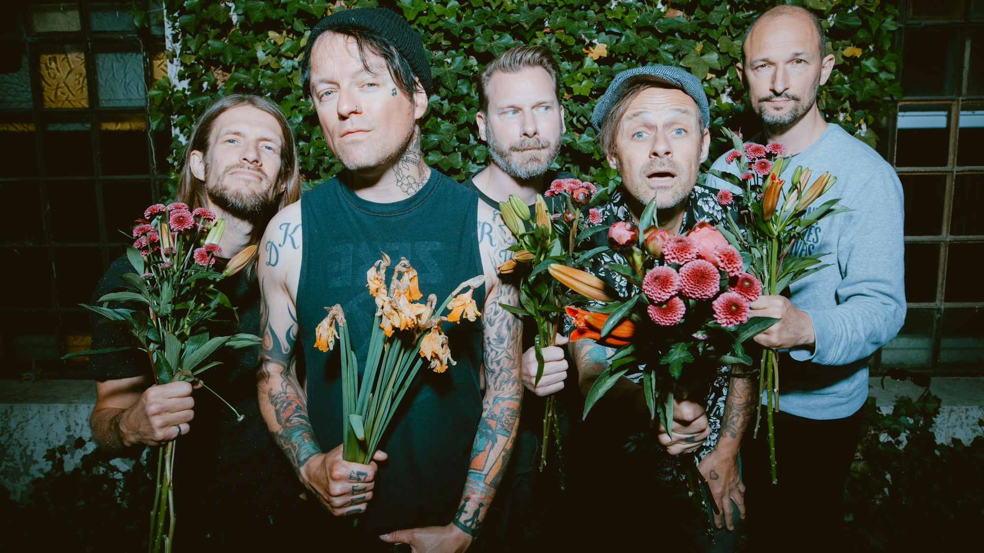 Pressebild der Donots: Eike Herwig (v. l.), Guido Knollmann, Jan-Dirk „Purgen“ Poggemann, Ingo Knollmann und Alex Siedenbiedel halten Blumensträuße und gucken in die Kamera.