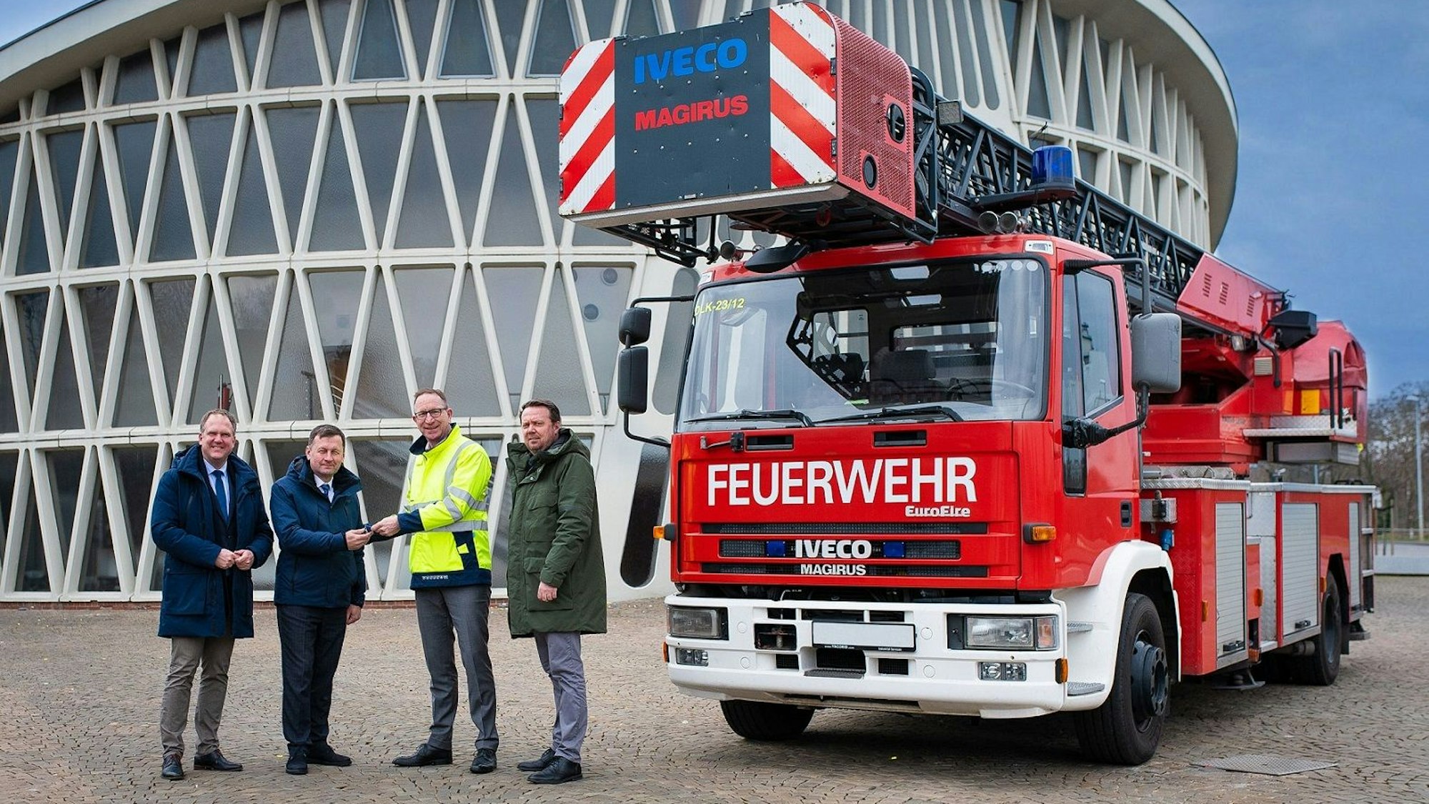 Die vier Männer stehen vor dem Feierabendhaus in Knapsack und neben ihnen steht der Drehleiterwagen.