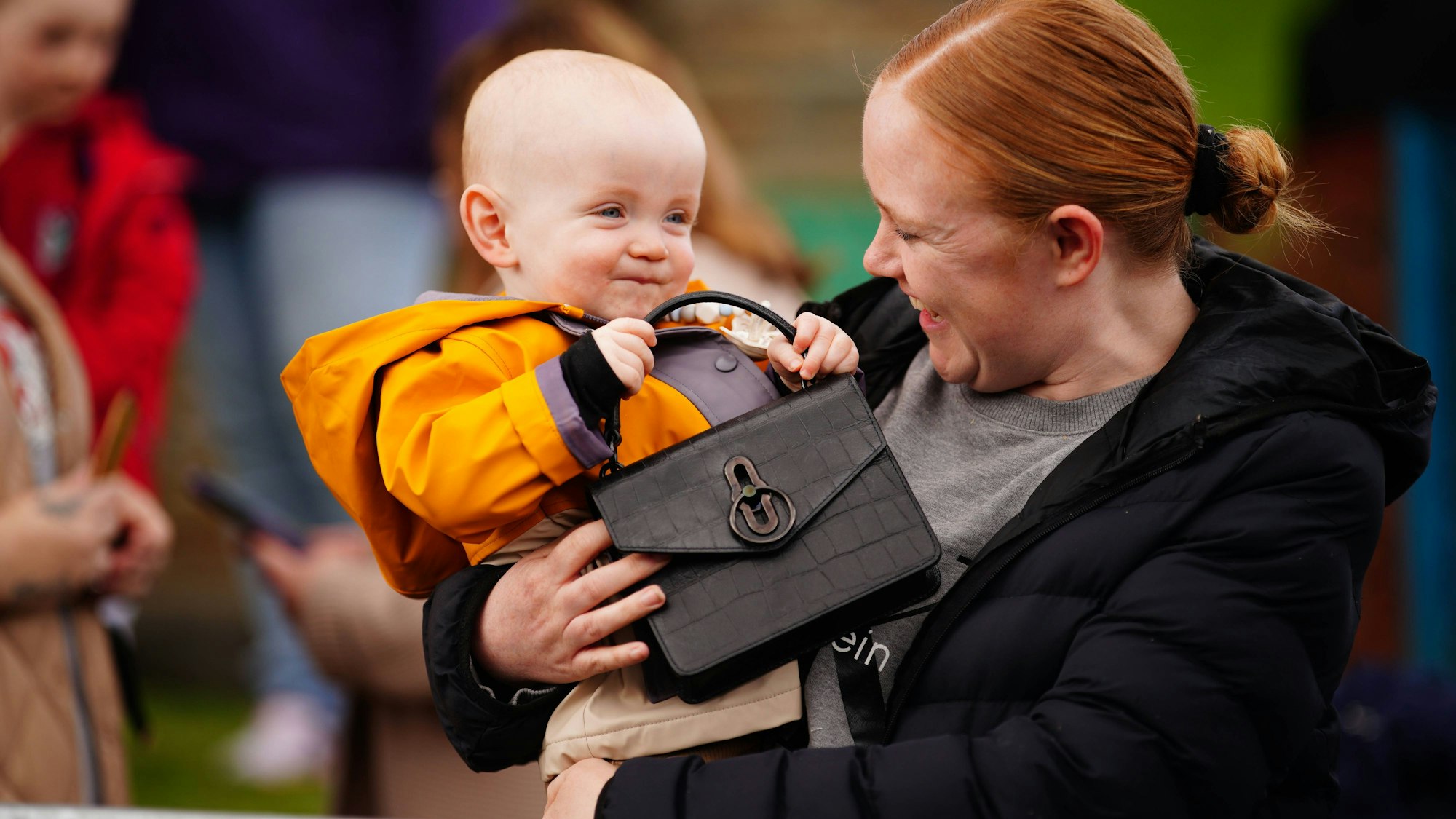 Der einjährige Daniel Williams hält mit seiner Mutter Lucy die Handtasche von Kate Middleton, der Prinzessin von Wales, während eines Besuchs des Aberfan Memorial Garden in Wales, Vereinigtes Königreich.