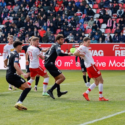 Der Regensburger Torhüter Jonas Urbig (r) klatscht einen Kopfball auf der Linie weg.