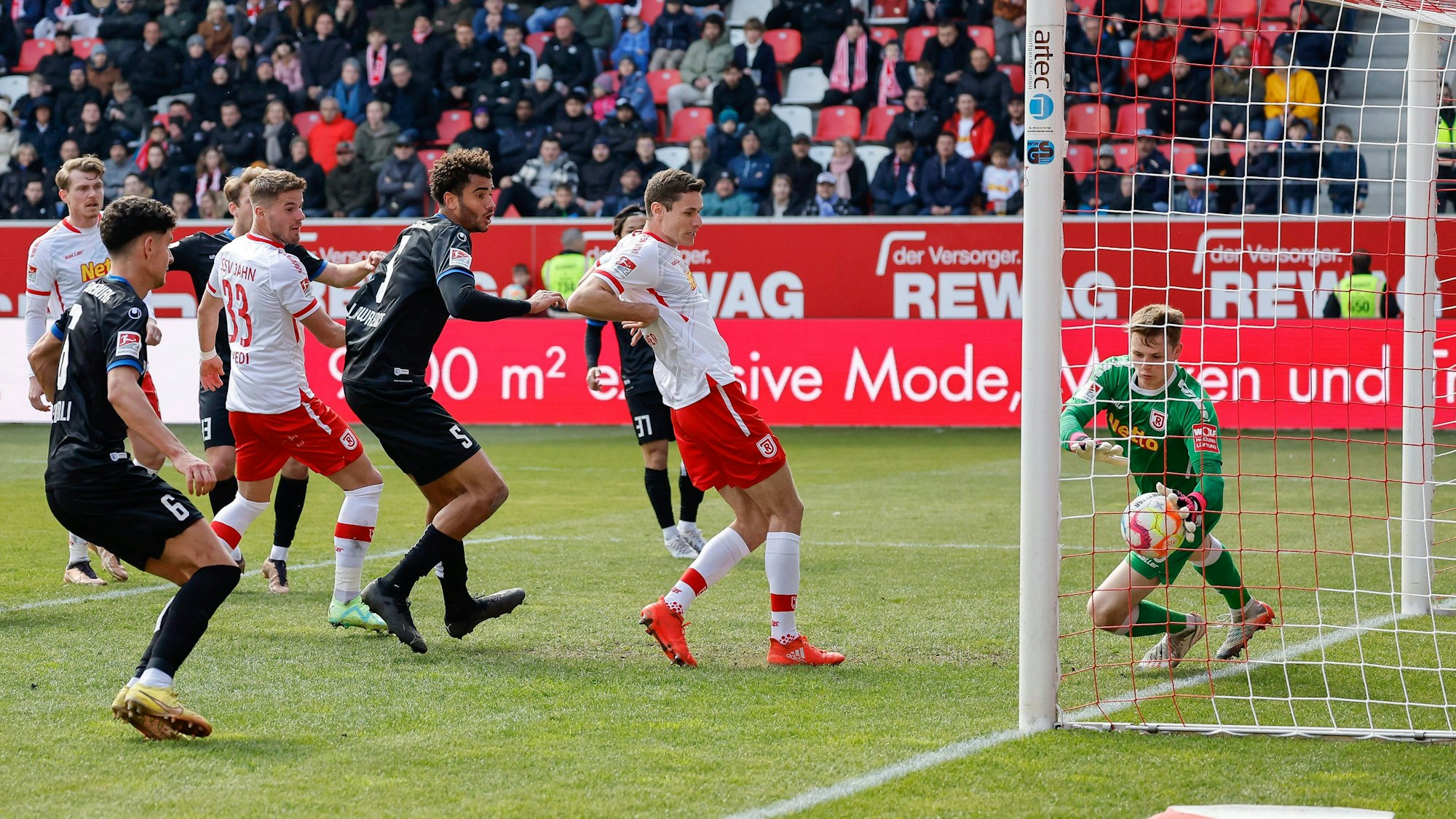 Der Regensburger Torhüter Jonas Urbig (r) klatscht einen Kopfball auf der Linie weg.