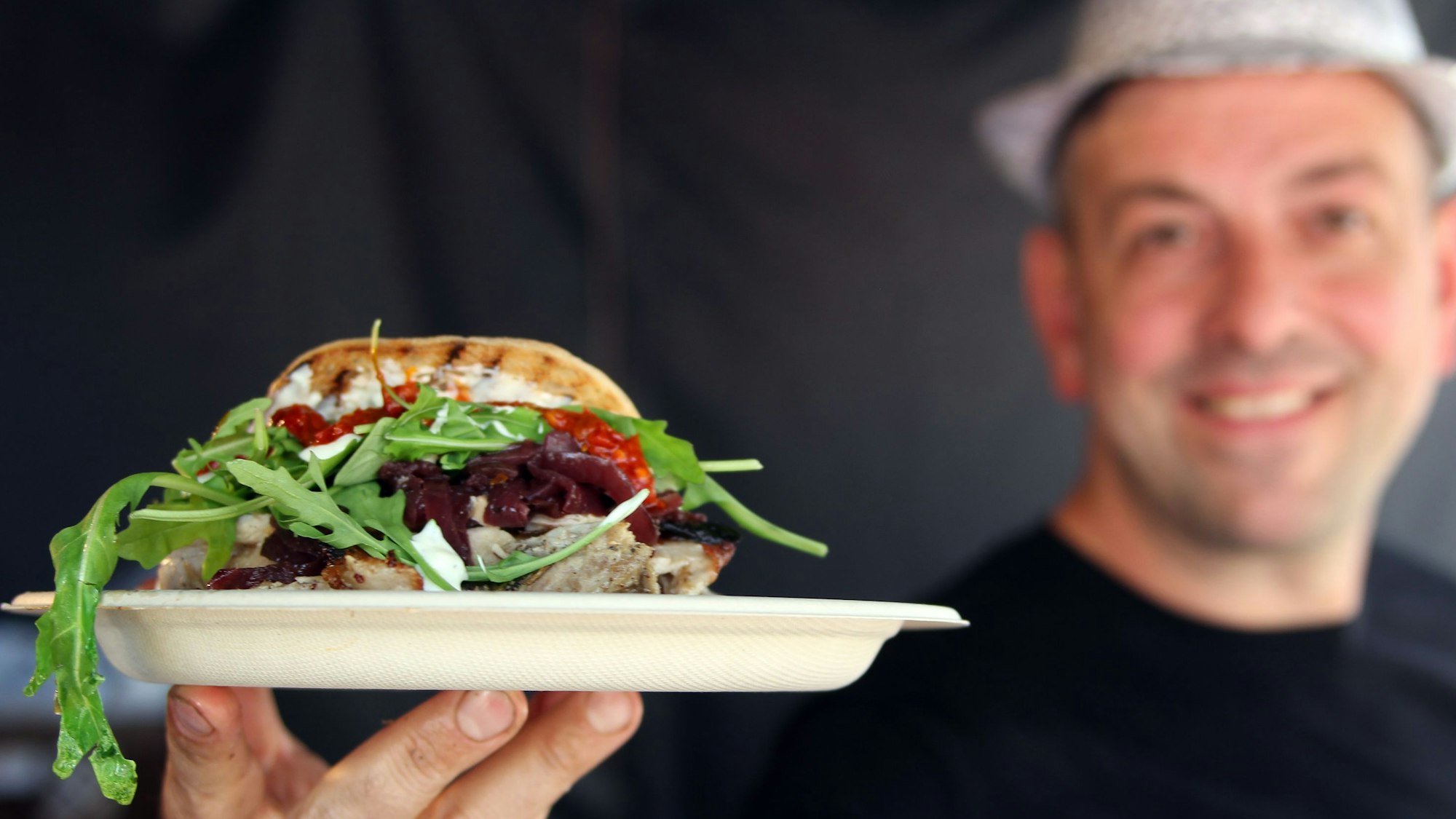 Ein Koch zeigt ein Spanferkelbraten im Focaccia-Brot. Beim Wesselinger Streetfood-Festival gehörte es im Jahr 2022 gehörte es zu den Top-Angeboten. Auch in Bedburg soll es kulinarisch abwechslungsreich zugehen.