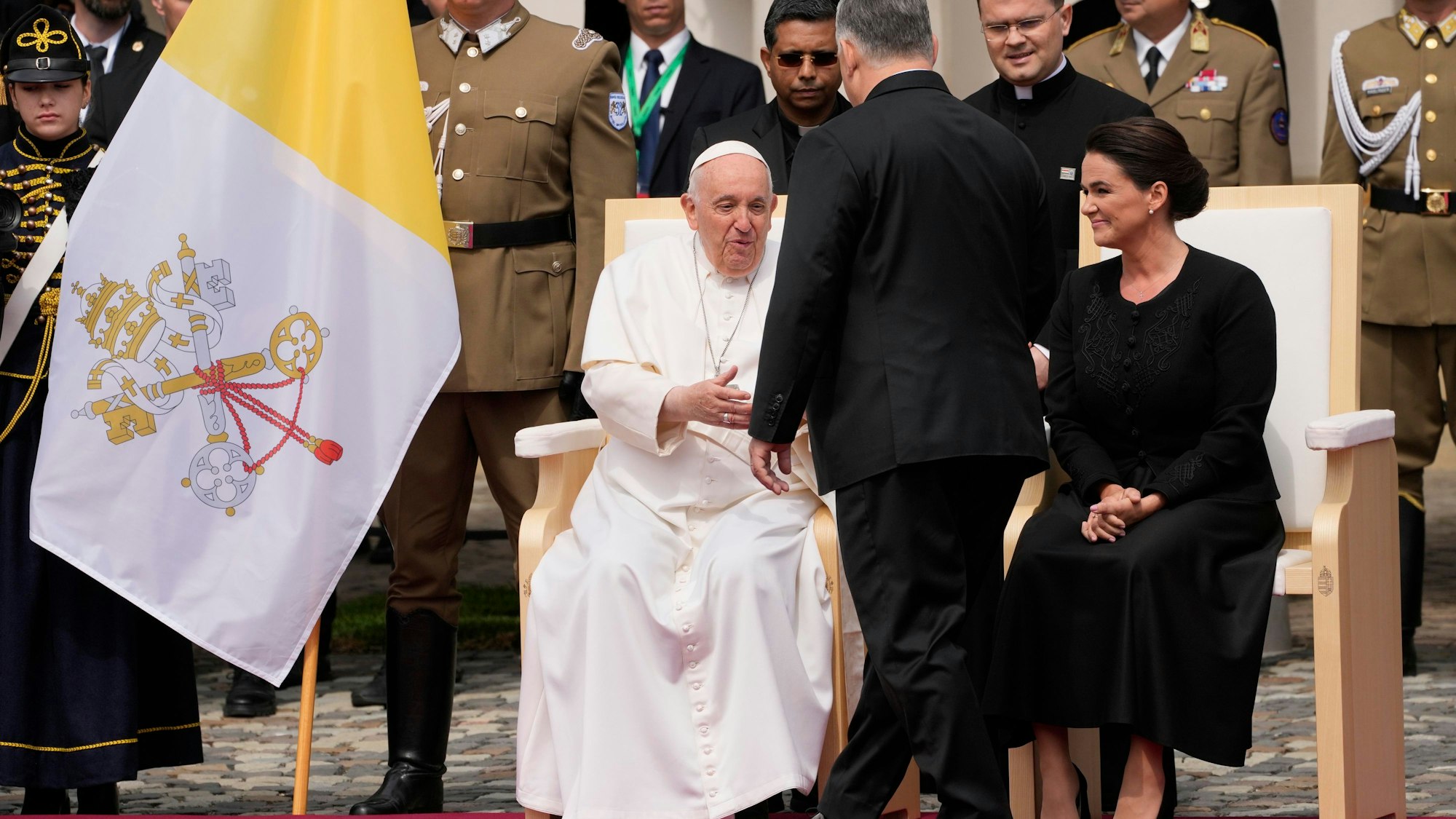Papst Franziskus (l), wird von Viktor Orban, Ministerpräsident von Ungarn, auf dem Platz vor dem Palais Sandor begrüßt. Rechts sitzt Katalin Novak, Präsidentin von Ungarn.