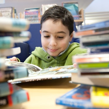 Ein Kind liest ein Buch in der Stadtbibliothek in Melle.