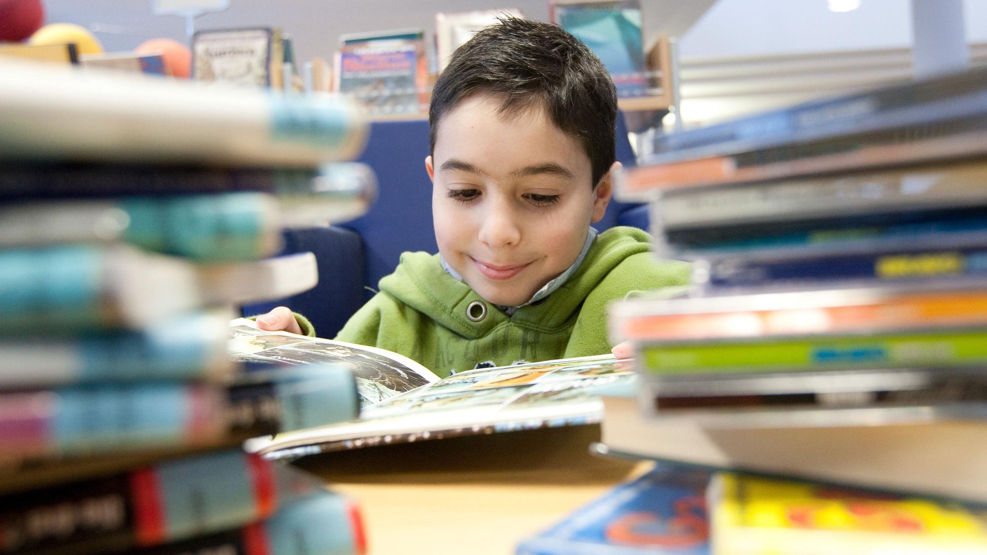 Ein Kind liest ein Buch in der Stadtbibliothek in Melle.