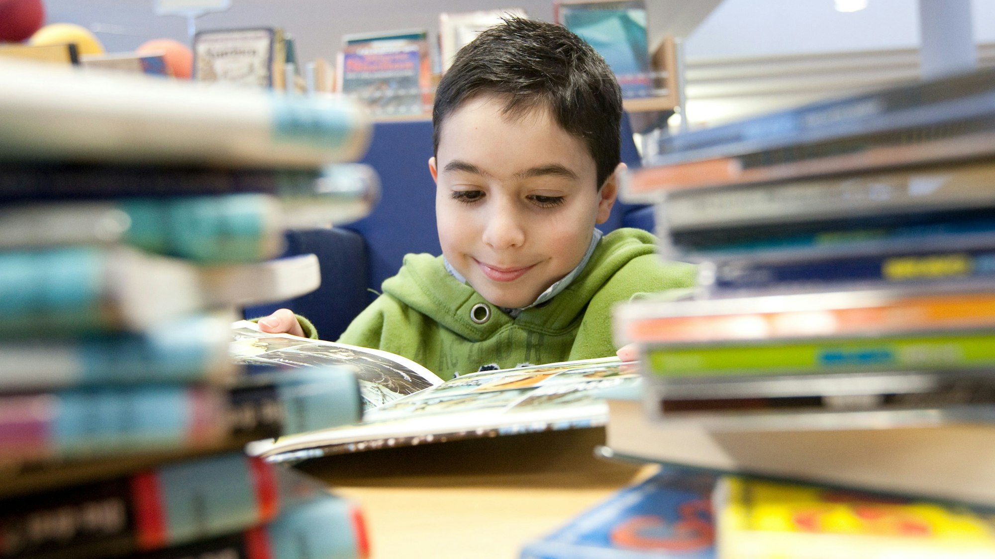 Ein Kind liest ein Buch in der Stadtbibliothek in Melle.