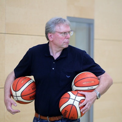 Manager Frank Beier trägt drei Basketbälle unter den Armen.