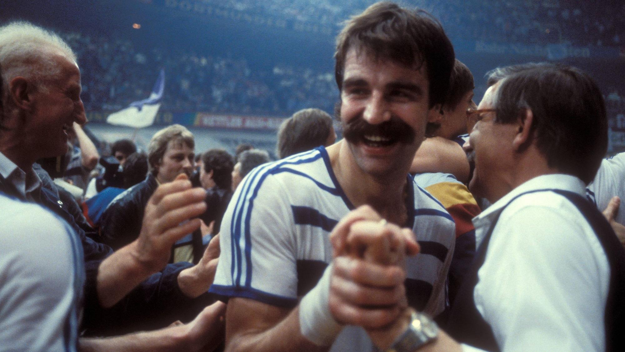 Im Bild ist ein Menschenauflauf zu sehen, die Personen freuen sich und gratulieren einander. Mittendrin ist Handball-Legende Heiner Brand.