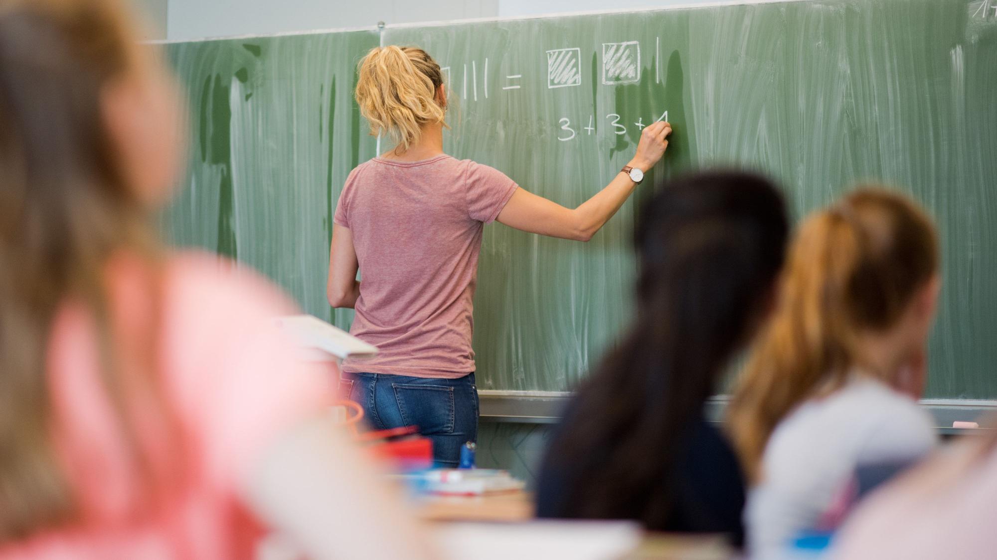 Eine junge Lehrerin schreibt an einer Schultafel. Am Dienstag findet in Düsseldorf eine Pressekonferenz zum landesweiten Rollout der Computer-Arbeitsplattform für Lehrer, «Logineo NRW», statt.