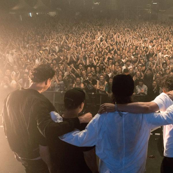 Die Band steht Arm in Arm vor ihren Zuschauern und Zuschauerinnen auf der Bühne.