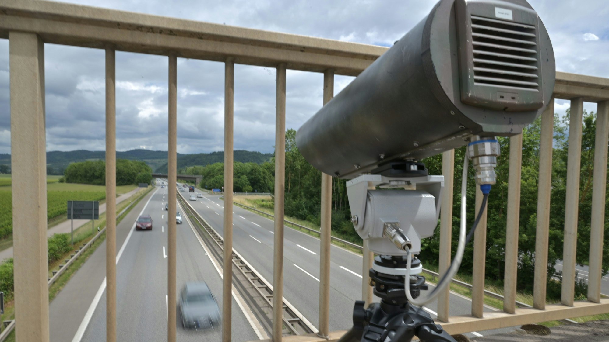 Eine Monocam zur Aufzeichnung von Handysündern am Steuer steht auf einer Brücke über einer Autobahn.