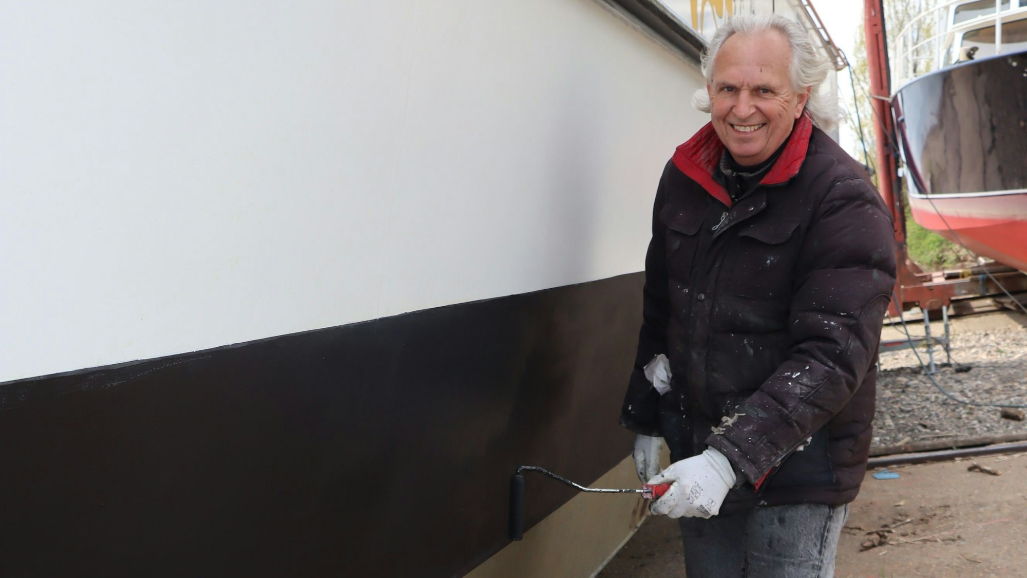 Weisbarth steht neben dem Fisch und hat eine Farbrolle in der Hand. Er blickt lächelnd in die Kamera.