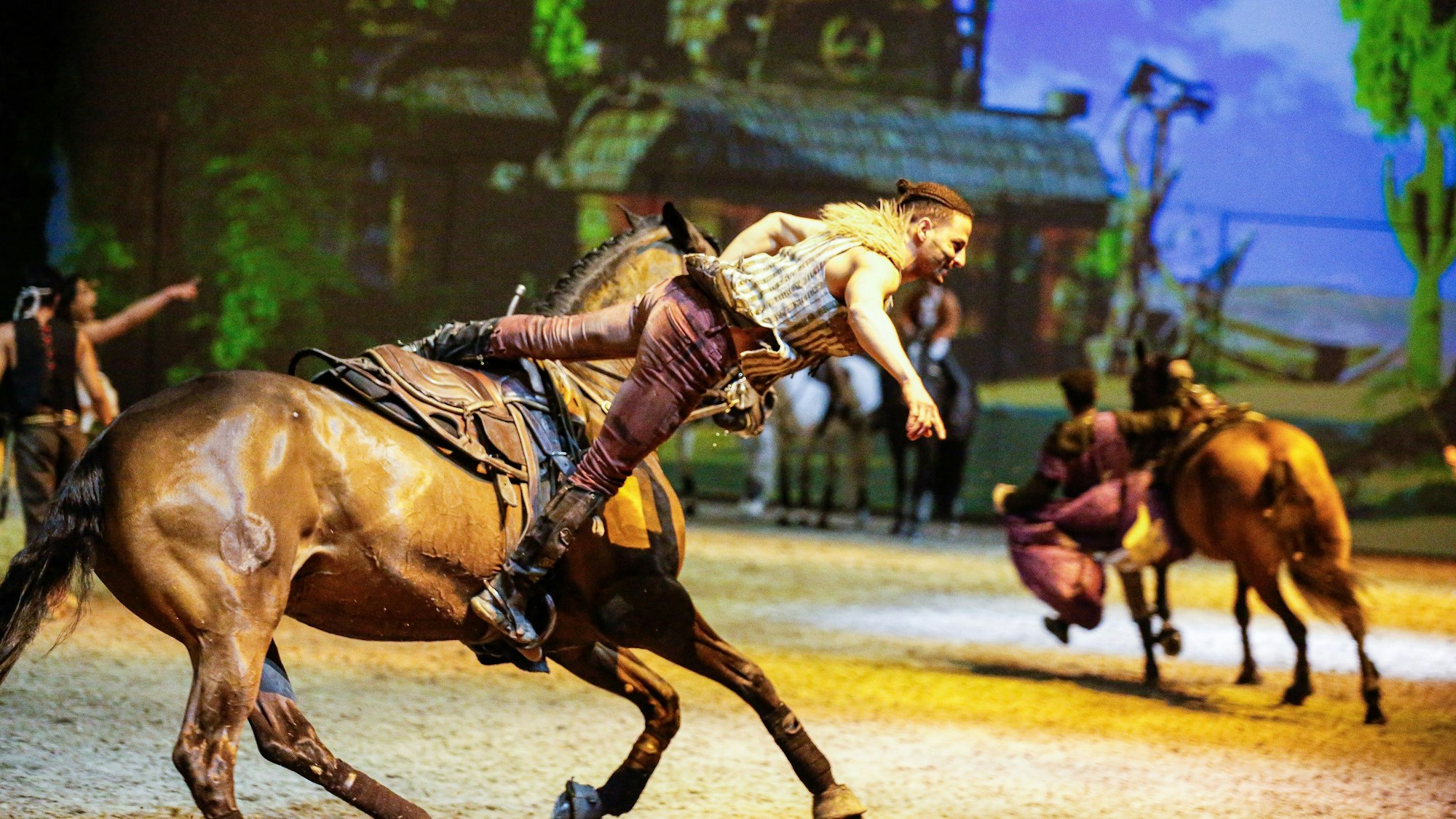 Ein Trickreiter bei einem Stunt auf einem Pferd.